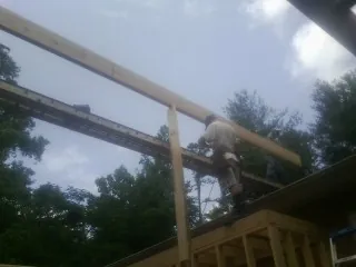 Carpenter setting a ridge beam over a new addition frame — Ice Dam Removal by Roofing Brothers in Coleharbor