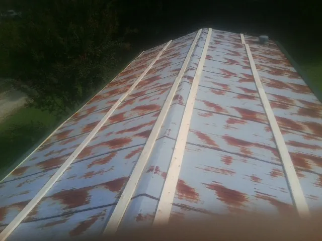 Rusted metal roof panels with new wood purlins before replacement — Storm Damage Roof Repair in Coleharbor by Roofing Brothers