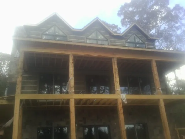 Dormers and porch framing on a large log home under construction — Roof Coating work by our crew in Coleharbor