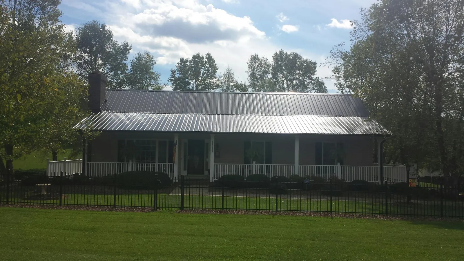 Gray metal roof on a brick ranch with a full width front porch — Gutter Guard Installation work by our crew in Coleharbor
