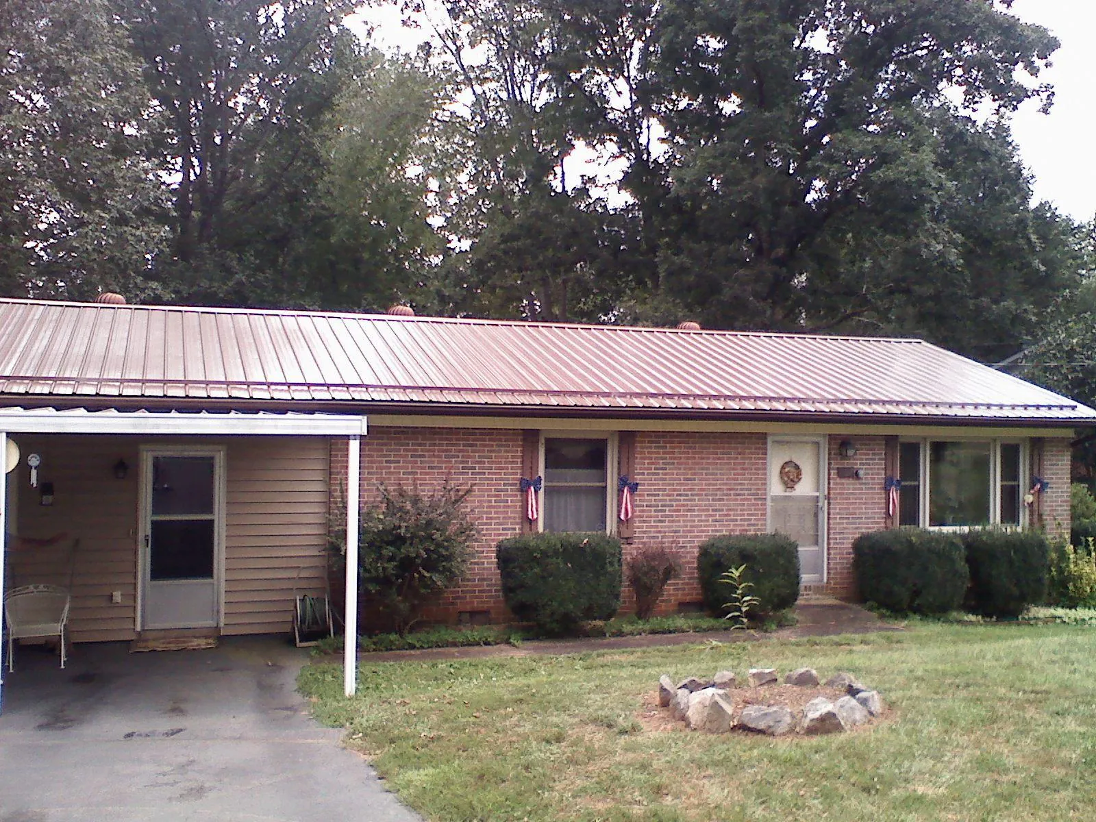 Bronze metal roof and carport on a brick ranch home — Roof Repair work by our crew in Coleharbor