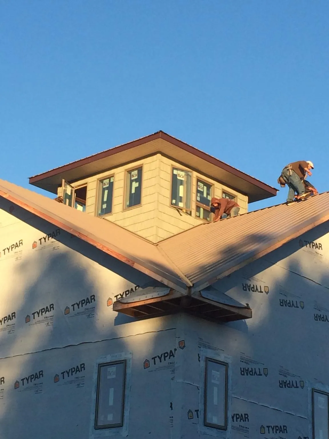 Roofers working around a rooftop cupola on a new metal roof at sunset — Roof Waterproofing in Coleharbor by Roofing Brothers